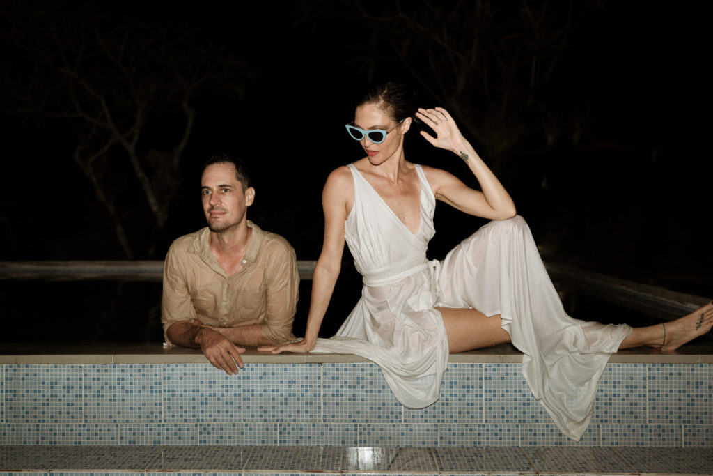 bride and groom sitting at edge of pool at their bali elopement