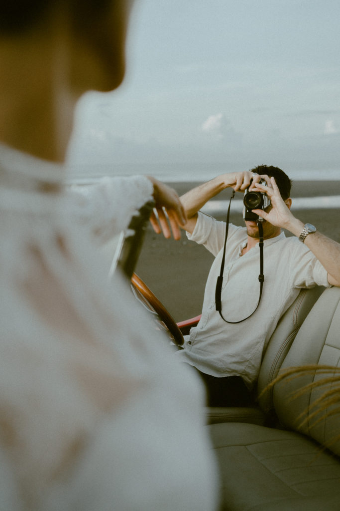 groom holding a film camera taking a photo of his bride at their bali elopement