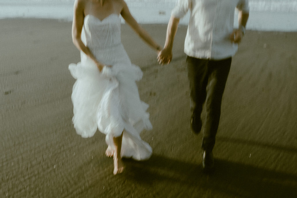 bride and groom running on beach while holding hands at their bali elopement