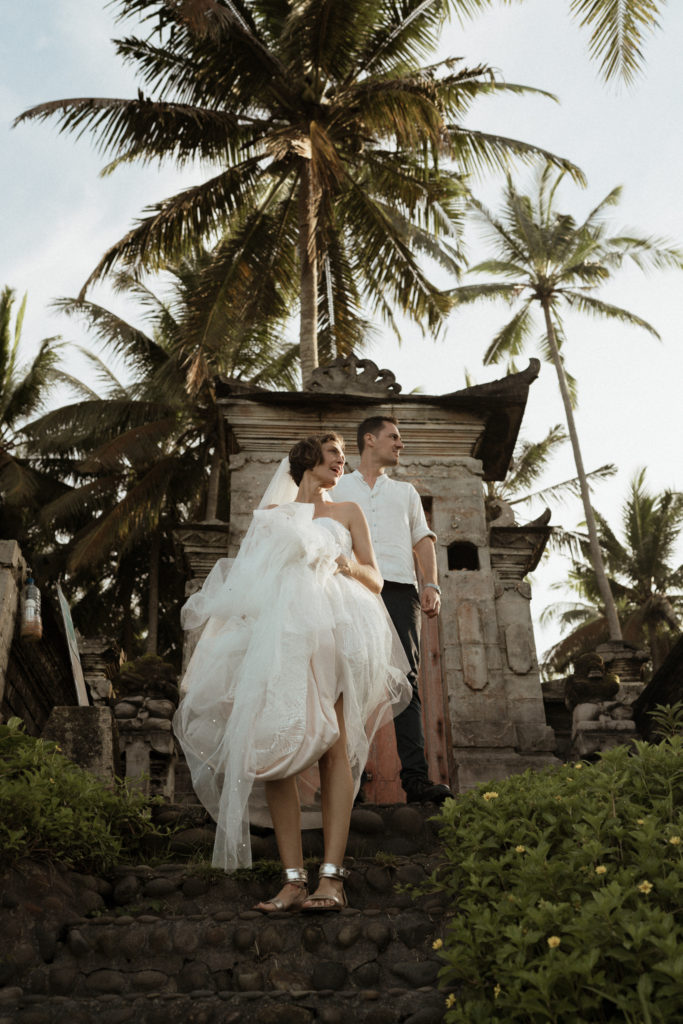 bride and groom standing near ruins at bali elopement