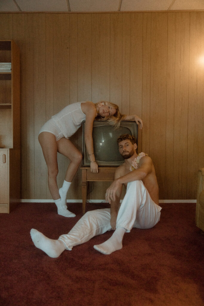 couple posing with vintage tv at their engagement photos in portland