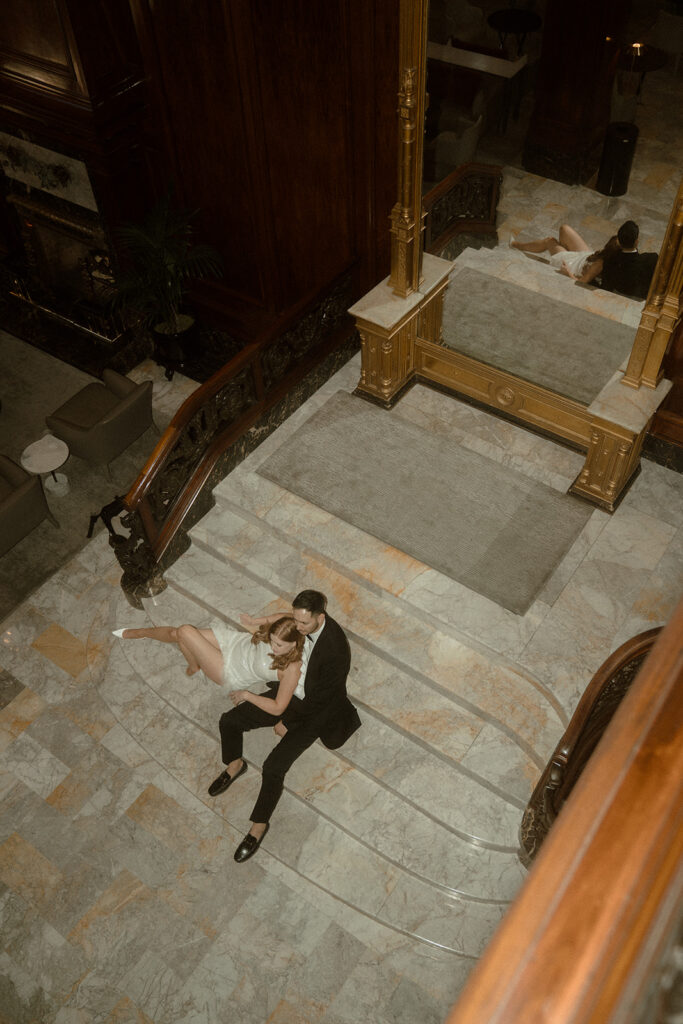 Intimate moment captured between couple sitting on the steps of The Benson Hotel's grand staircase for their Portland engagement photos