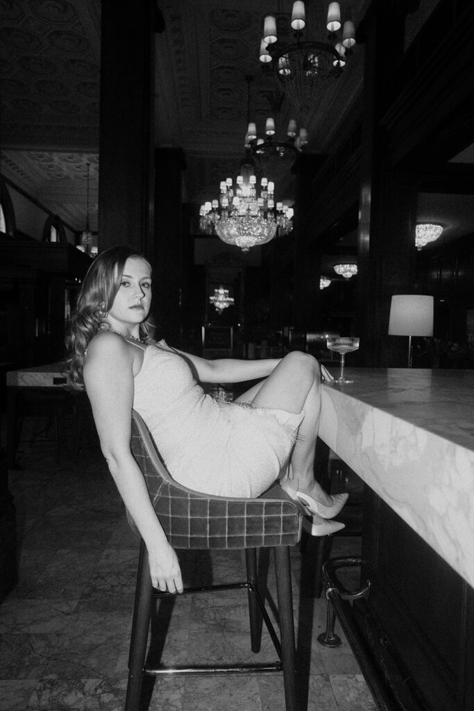 woman sitting at bar during engagement photos at the benson hotel in portland