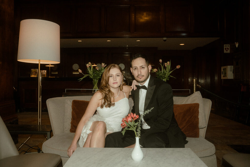 couple sitting on couch at benson hotel in Portland during their engagement photos